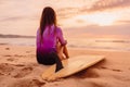 Surfer woman posing with surfboard on the beach at sunset Royalty Free Stock Photo