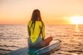 Woman relaxing on stand up paddle board, quiet sea with warm sunset colors. Royalty Free Stock Photo