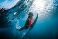 Surfer woman with surfboard dive underwater with under wave and sunlight in transparent ocean Royalty Free Stock Photo