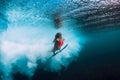 Surfer woman with surfboard dive underwater with under ocean wave.