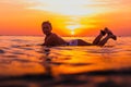 Surfer woman on a surfboard in ocean. Surfgirl at sunset