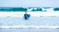 Surfer woman with surfboard is walking and watching the waves. Royalty Free Stock Photo