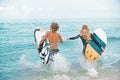 Surfers at the beach- Smiling couple of surfers run on the sea and having fun in summer. Extreme sport and vacation Royalty Free Stock Photo