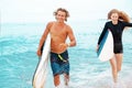 Surfers at the beach- Smiling couple of surfers walking on the beach and having fun in summer. Extreme sport and Royalty Free Stock Photo