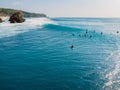 Surfers in blue ocean at Bali. Aerial view of tropical island with wave
