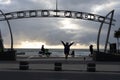Surfers Paradise iconic waterfront sculptural sign frames young female tourist posing for selfie as woman rides by on Lime