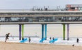 Surfers on Scheveningen Beach in the Netherlands with the pier in the background Royalty Free Stock Photo
