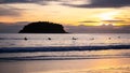 Surfers sitting on surfboard in water at the beach with sunset.