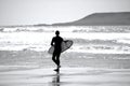 Surfers standing by the water`s edge at Llangennith Beach on the Gower Peninsula