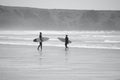 Surfers standing by the water`s edge at Llangennith Beach on the Gower Peninsula