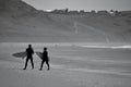 Surfers standing by the water`s edge at Llangennith Beach on the Gower Peninsula