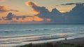 Surfers walking along and evening beach with a sunset behind them Royalty Free Stock Photo