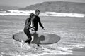 Surfers walking back from the water`s edge at Llangennith Beach on the Gower Peninsula