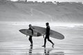 Surfers walking bavk from the water`s edge at Llangennith Beach on the Gower Peninsula