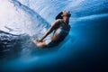 Surfgirl dive underwater under wave. Duck dive under barrel wave in blue ocean