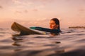 Surfgirl with perfect body on a surfboard floating in ocean