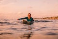 Surfgirl with perfect body on a surfboard floating in ocean.