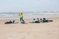 Surfing coach instructs novice surfers on the beach near the open water