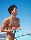 Surfing, fitness and body happy man at a beach with surfboard for training, freedom or fun. Smile, adventure and male Royalty Free Stock Photo