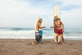 Surfing. Handsome Surfers Standing On Sunny Beach. Cheerful Men Giving Fist Bump Near Surfboards In Sand. Royalty Free Stock Photo