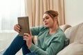 Surfing internet. Young beautiful girl in casual clothes relaxing on sofa in the living room at home and using digital Royalty Free Stock Photo