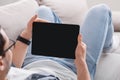 Surfing the internet. Man with smartwatch on couch at home and holds tablet with blank screen Royalty Free Stock Photo