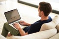 Surfing the net from the comfort of home. High angle shot of a young man using his laptop while sitting on the sofa at Royalty Free Stock Photo