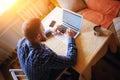 Surfing the net in office. Confident young man working on laptop and smiling while sitting at his working place in office