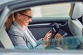 Surfing net on the way to office, side view of happy beautiful business woman sitting on back seat in the car, using Royalty Free Stock Photo