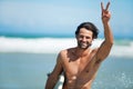 Surfing, portrait and happy man with peace hands at a beach for travel, freedom or adventure. Face, smile and male
