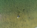 Surfing sport. Man on a white board in the ocean, Sunny day, Aerial top view. Water texture. Outdoor activity concept. Copy space