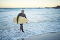 Surfing, surfboard and senior man on beach for water sports while walking on adventure after riding sea waves on a Royalty Free Stock Photo
