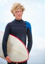 Surfs up. A young man standing on the beach holding a surfboard.