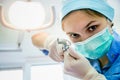 The surgeon dentist in mask holding forceps making tooth extraction