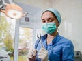 The surgeon dentist in mask holding forceps preparing for tooth extraction at clinic