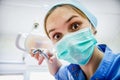 The surgeon dentist in mask holding forceps preparing for tooth extraction at clinic. Crazy dentist