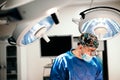 Surgeon doctor performing operation using special lamp lighting, wearing blue surgical mask Royalty Free Stock Photo