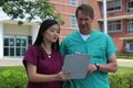 Surgeon or Doctor or Physician or Clinician and Asian Nurse Stand in Front of Hospital Discussing Patient Chart Royalty Free Stock Photo