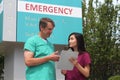 Surgeon, Doctor, Physician, Clinician and Asian Nurse Wearing Scrubs Stand in Front of Hospital Emergency Room Sign