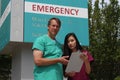 Surgeon, Doctor, Physician, Clinician and Asian Nurse Wearing Scrubs Stand in Front of Hospital Emergency Room Sign Royalty Free Stock Photo