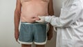 surgeon doing a medical checkup by palpating the belly on adipose tissues, cellulite, on a man patient with a flacid