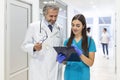 Surgeon and Female Doctor Walk Through Hospital Hallway, They Consult Digital Tablet Computer while Talking about Patient`s Healt Royalty Free Stock Photo