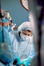 Surgeon and his assistant performing cosmetic surgery in hospital operating room. Surgeon in mask wearing loupes during Royalty Free Stock Photo