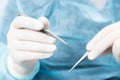 Surgeon holding a surgical needle holder with silk thread. Close-up