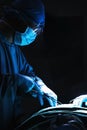 Surgeon looking down, working, and holding surgical equipment with patient lying on the operating table