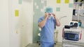 Surgeon puts on sterile mask and magnifying binocular glasses before surgery in operating room