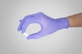 Surgeon`s hand in a blue medical glove holds a white pill isolated on neutral gray background Royalty Free Stock Photo