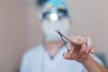 Surgeon in special medical clothes holds surgical metal scissors in his hand. Focus on the instrument. Operation process Close-up.