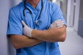 Surgeon standing with arms crossed in corridor at hospital Royalty Free Stock Photo