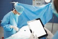 Surgeon using digital while nurse operating patient in operation room Royalty Free Stock Photo